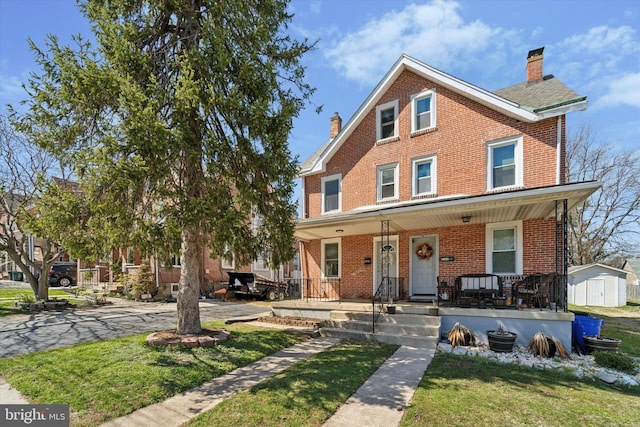view of front of home featuring brick siding, a porch, and a chimney