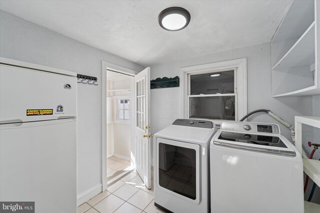 clothes washing area featuring washing machine and clothes dryer, light tile patterned flooring, and laundry area