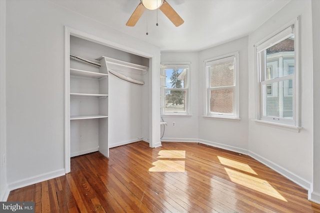 unfurnished bedroom featuring a closet, baseboards, a ceiling fan, and hardwood / wood-style floors