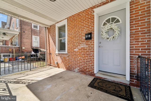 doorway to property featuring fence and brick siding