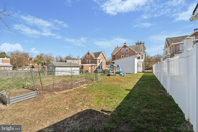 view of yard featuring a fenced backyard, a vegetable garden, and a residential view