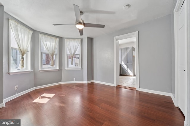 unfurnished bedroom featuring wood finished floors, baseboards, and a ceiling fan