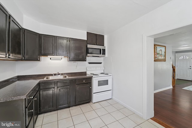 kitchen with stainless steel microwave, baseboards, light tile patterned flooring, electric stove, and a sink