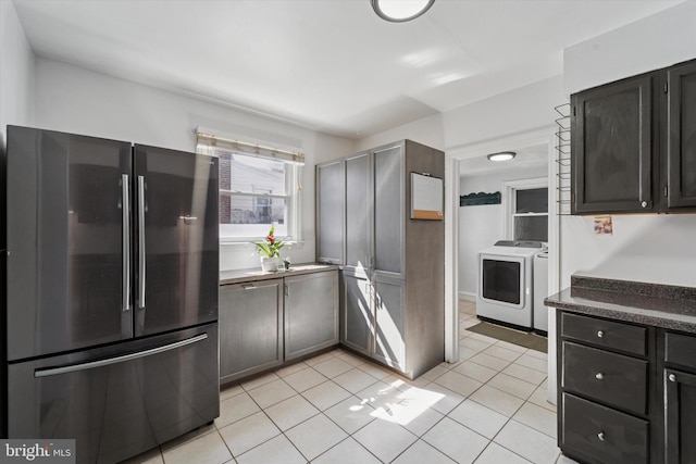 kitchen featuring washer / dryer, freestanding refrigerator, light tile patterned flooring, and dark countertops