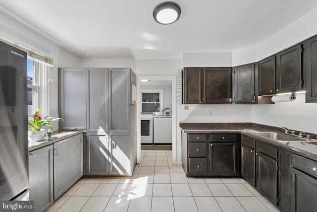 kitchen featuring a sink, dark countertops, independent washer and dryer, refrigerator, and light tile patterned flooring