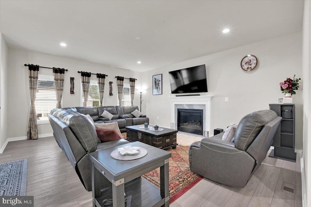 living area featuring light wood-type flooring, recessed lighting, baseboards, and a fireplace