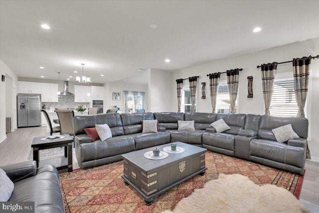 living room with baseboards, light wood-type flooring, recessed lighting, and a notable chandelier