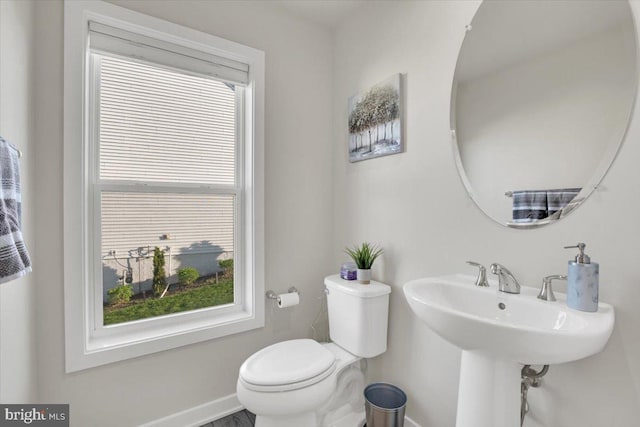 half bath featuring baseboards and toilet