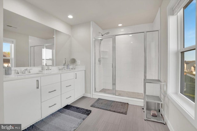 full bathroom with visible vents, a sink, a stall shower, and a wealth of natural light