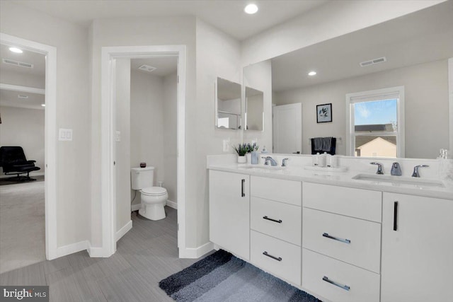 full bathroom with visible vents, a sink, double vanity, and toilet