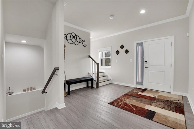 entryway with crown molding, stairs, baseboards, and wood finished floors