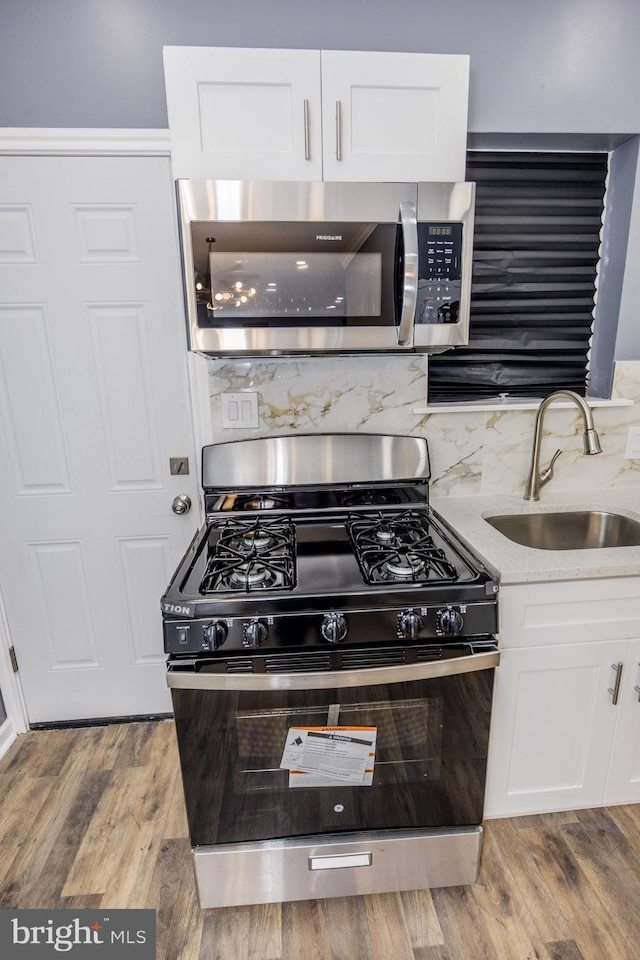 173 W Seymour St, Philadelphia, PA 19144 - kitchen featuring white cabinets, a sink, light wood finished floors, stainless steel appliances, and light stone counters