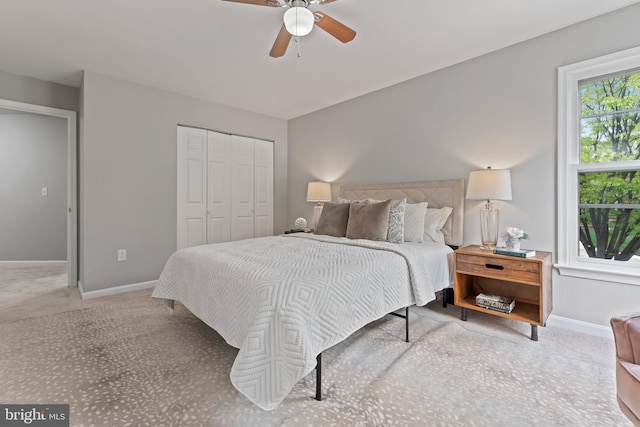 carpeted bedroom with a closet, baseboards, and ceiling fan