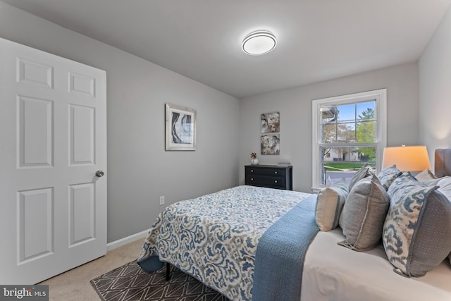 bedroom with light colored carpet and baseboards