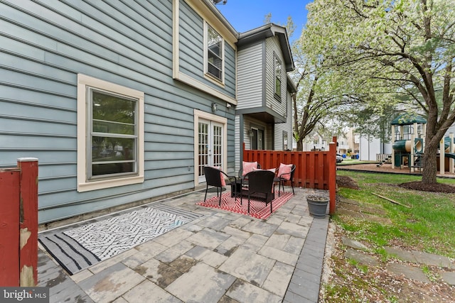 view of patio / terrace with french doors, fence, and a playground
