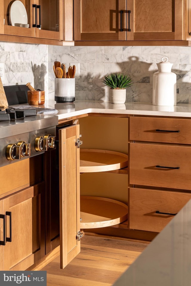 room details with stainless steel gas cooktop, tasteful backsplash, light wood finished floors, and light countertops
