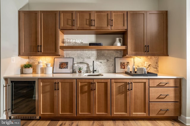 bar with tasteful backsplash, light wood-type flooring, a sink, and wine cooler