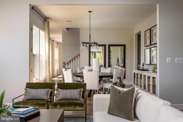 living area featuring stairs, a notable chandelier, wood finished floors, and a healthy amount of sunlight