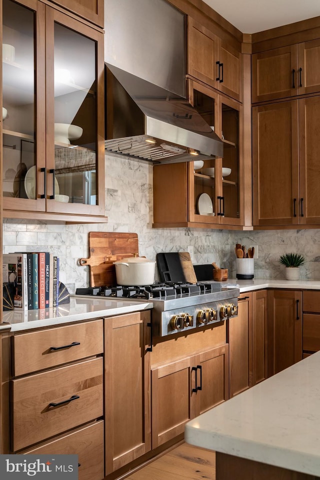 kitchen with wall chimney range hood, tasteful backsplash, stainless steel gas stovetop, and light countertops