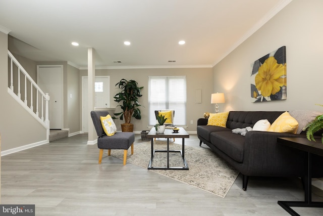 living area featuring light wood finished floors, baseboards, visible vents, and stairs