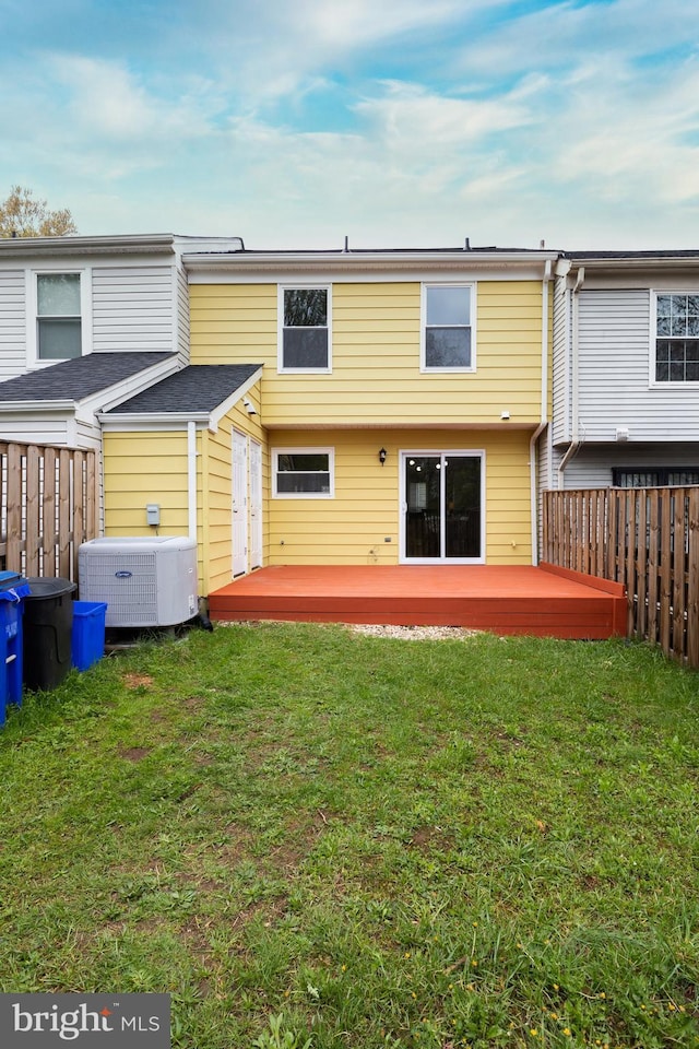 back of property with a yard, central air condition unit, a wooden deck, and fence