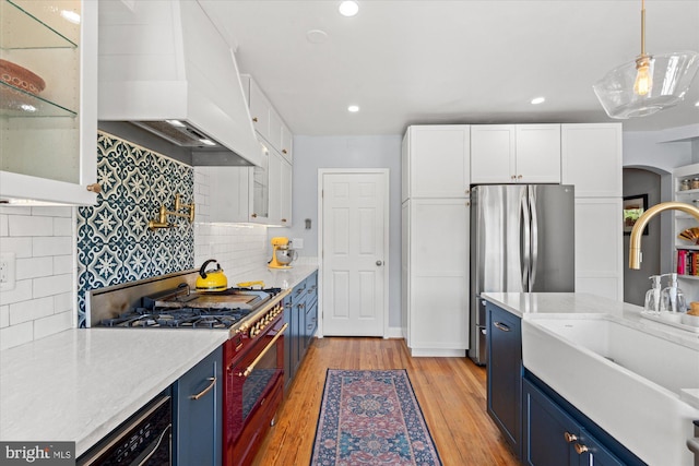 4935 New Hampshire Ave NW, Washington, DC 20011 - kitchen with premium range hood, blue cabinetry, white cabinetry, stainless steel appliances, and a sink