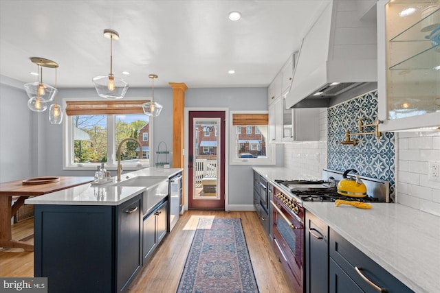 4935 New Hampshire Ave NW, Washington, DC 20011 - kitchen featuring custom exhaust hood, light wood-type flooring, light countertops, backsplash, and stainless steel appliances