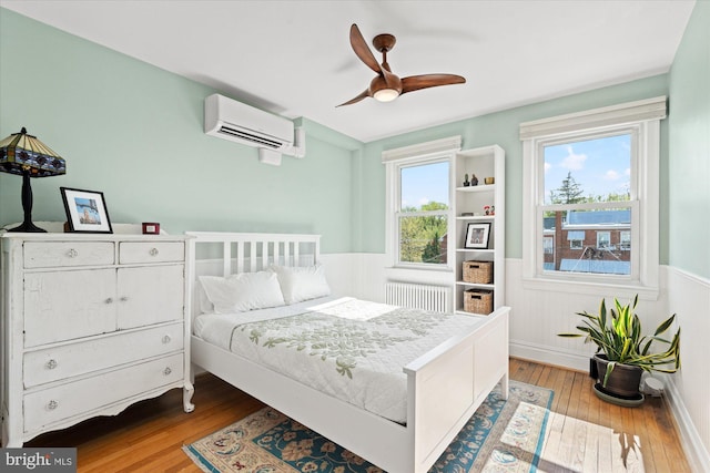 4935 New Hampshire Ave NW, Washington, DC 20011 - bedroom featuring a wall mounted AC, a ceiling fan, wainscoting, hardwood / wood-style floors, and radiator