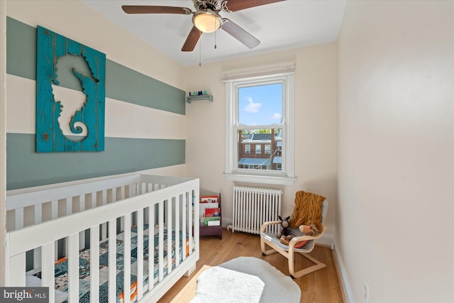 4935 New Hampshire Ave NW, Washington, DC 20011 - bedroom featuring baseboards, a ceiling fan, radiator heating unit, a nursery area, and wood finished floors