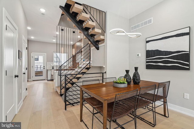 dining space with stairs, wood-type flooring, visible vents, and baseboards