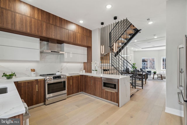 kitchen with wall chimney exhaust hood, modern cabinets, stainless steel range with electric stovetop, light wood-type flooring, and built in microwave
