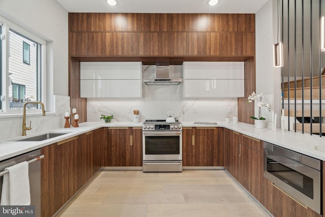 kitchen with backsplash, modern cabinets, wall chimney exhaust hood, stainless steel appliances, and a sink