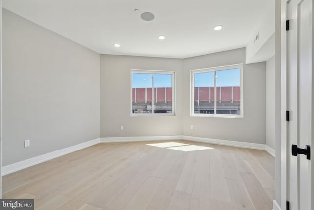 unfurnished room with light wood-type flooring, baseboards, visible vents, and recessed lighting