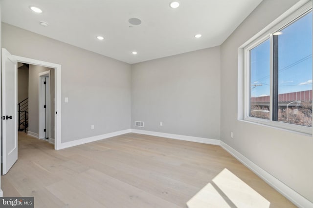 unfurnished room with visible vents, baseboards, light wood finished floors, recessed lighting, and stairs