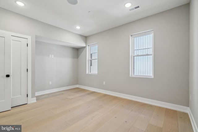 unfurnished room with light wood-style floors, a wealth of natural light, visible vents, and baseboards