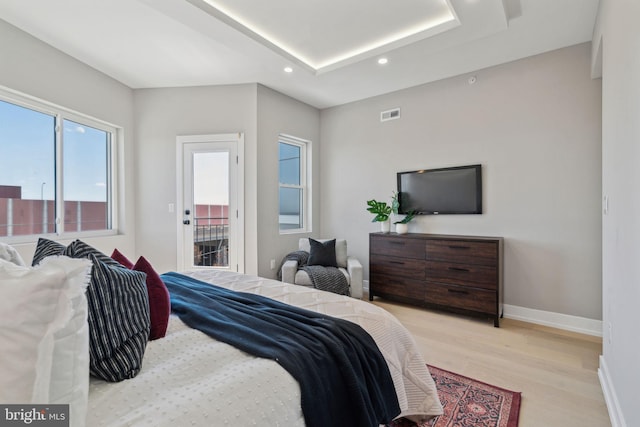 bedroom with visible vents, baseboards, light wood-style floors, a tray ceiling, and recessed lighting