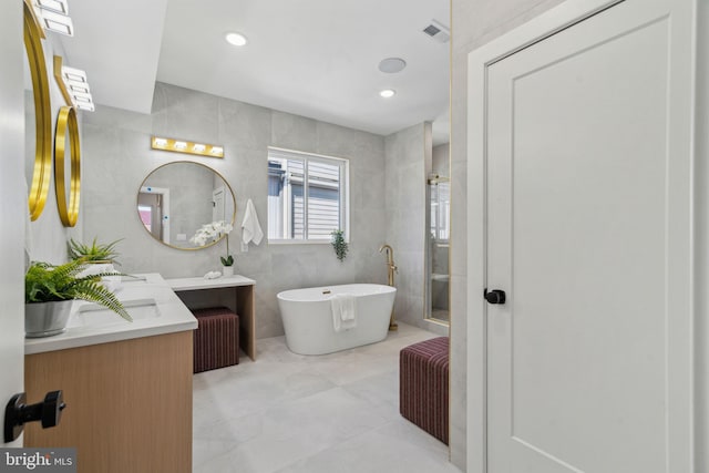 full bathroom with visible vents, a freestanding tub, tile walls, a shower stall, and vanity