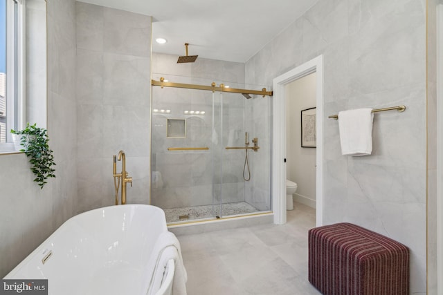 full bathroom with toilet, tile walls, a stall shower, and a soaking tub