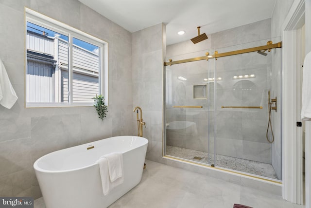 full bathroom with a stall shower, a freestanding tub, and tile walls