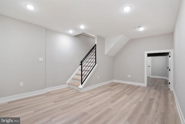 additional living space with stairs, light wood-style floors, and baseboards