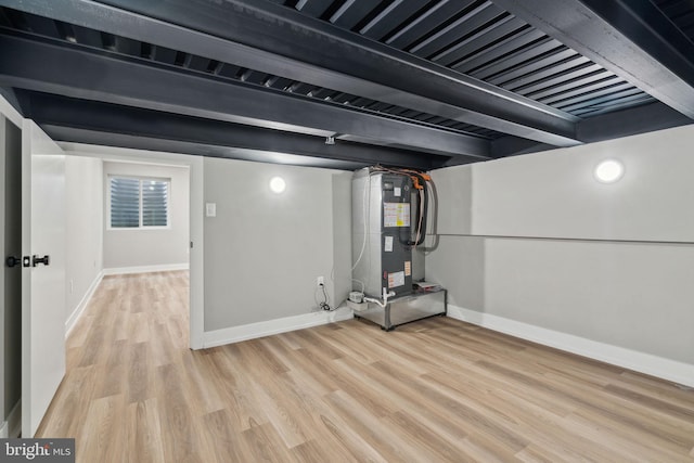 finished basement featuring light wood-type flooring, baseboards, and heating unit