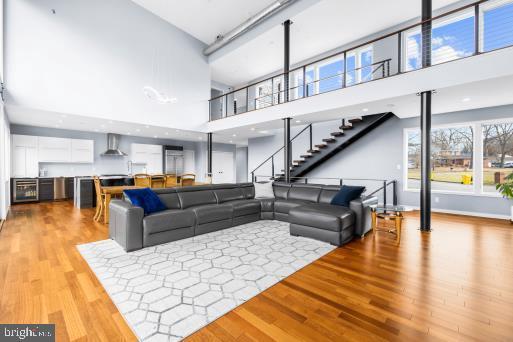 living room featuring a towering ceiling, wood finished floors, and stairway