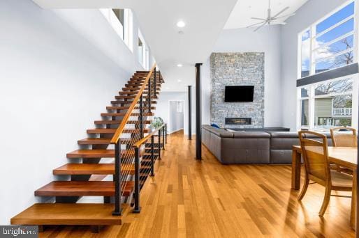 living room with a fireplace, light wood-type flooring, stairs, a high ceiling, and recessed lighting
