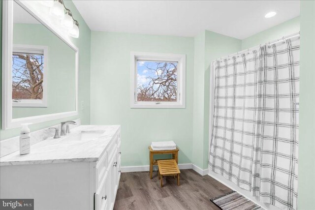 bathroom with baseboards, plenty of natural light, vanity, and wood finished floors