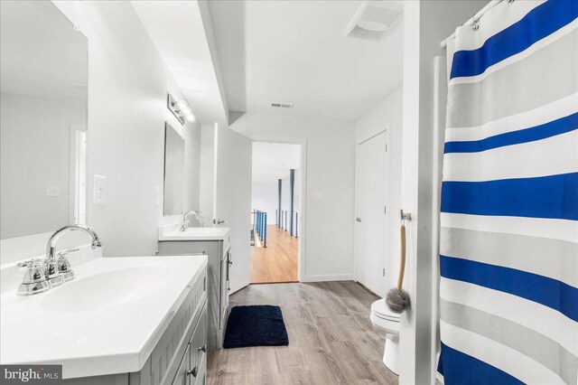 full bathroom featuring visible vents, a sink, wood finished floors, and two vanities