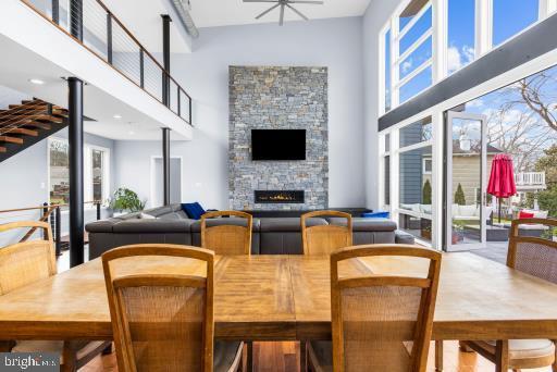 dining space with a high ceiling, a healthy amount of sunlight, ceiling fan, and a stone fireplace