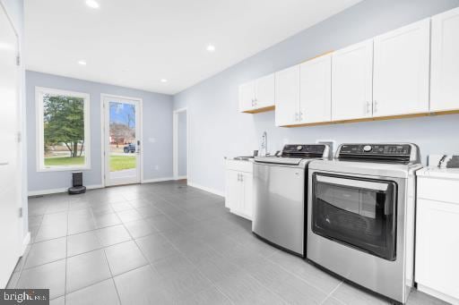 clothes washing area featuring separate washer and dryer, recessed lighting, cabinet space, and baseboards