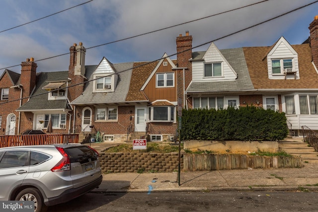 view of front facade with brick siding, a shingled roof, a residential view, and a chimney