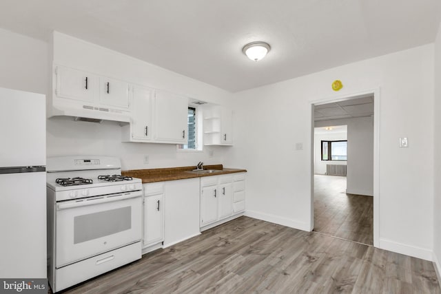 kitchen featuring a sink, dark countertops, white appliances, under cabinet range hood, and white cabinetry