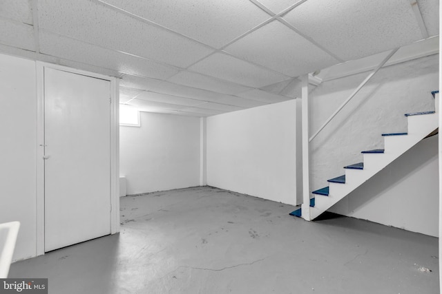 basement with a drop ceiling and stairway